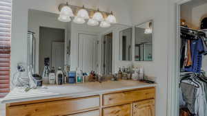 Bathroom featuring a spacious closet, vanity, and a shower stall