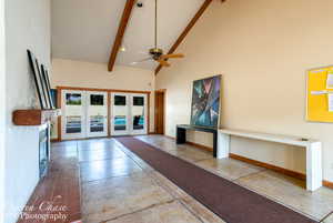 Unfurnished living room featuring high vaulted ceiling, beamed ceiling, and ceiling fan