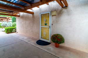 Property entrance with stucco siding and a pergola
