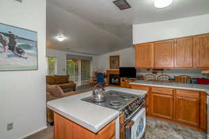 Kitchen featuring range with electric cooktop, a textured ceiling, open floor plan, light countertops, and lofted ceiling