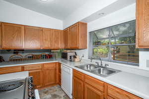 Kitchen featuring brown cabinets, light countertops, range with electric cooktop, white dishwasher, and lofted ceiling