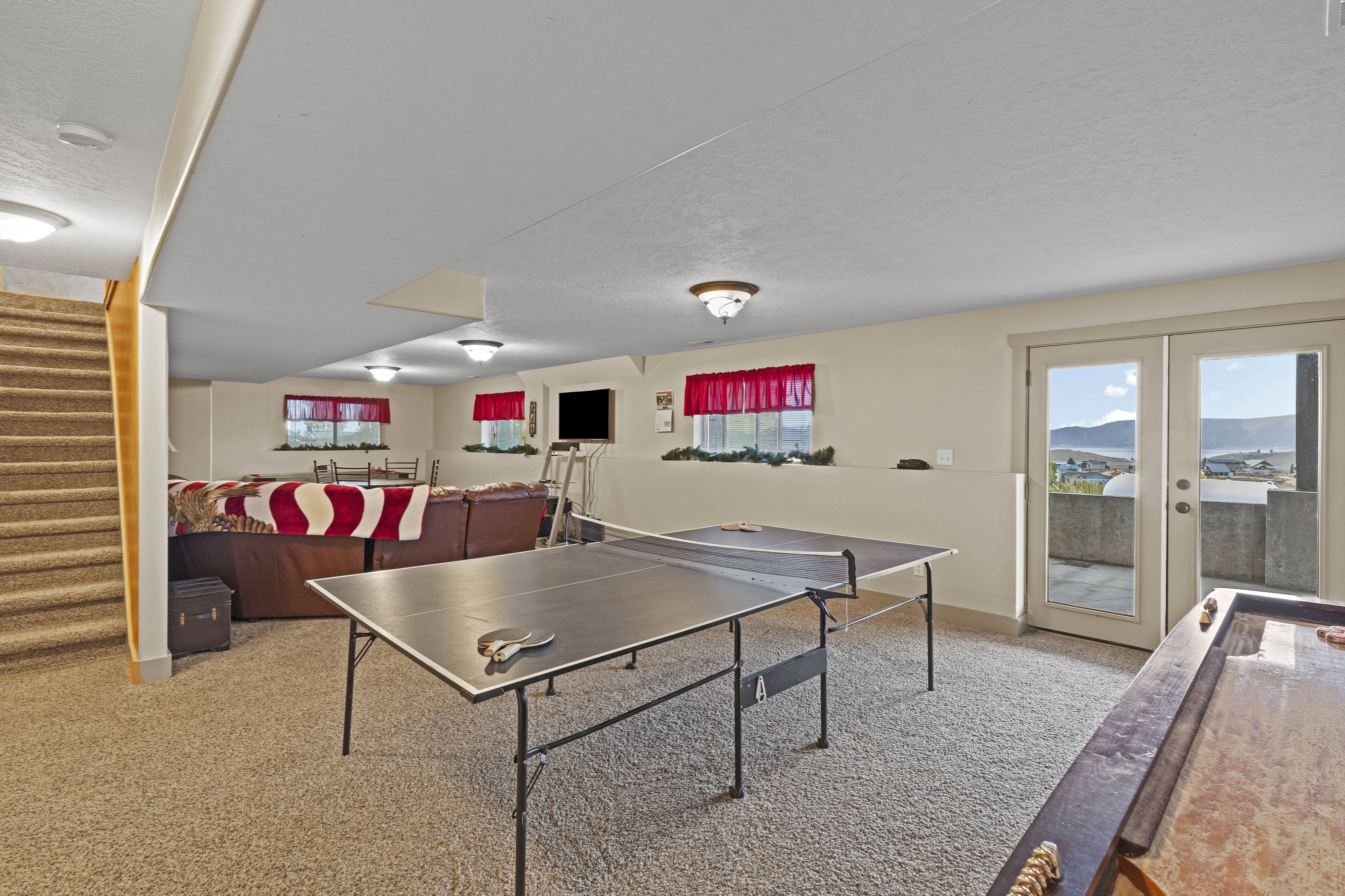 Rec room featuring light carpet, a textured ceiling, and french doors