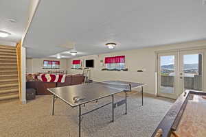 Rec room featuring light carpet, a textured ceiling, and french doors
