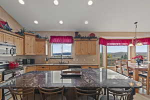 Kitchen with appliances with stainless steel finishes, dark stone countertops, a kitchen island, pendant lighting, and recessed lighting
