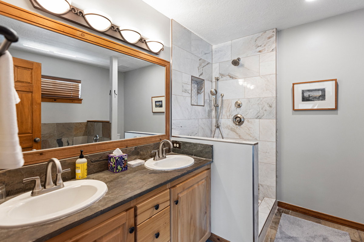 Full bath featuring a walk in shower, double vanity, and a textured ceiling