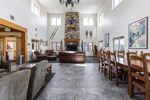 Living area featuring a stone fireplace, stone finish floors, and a high ceiling