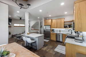 Kitchen with stainless steel appliances, recessed lighting, a breakfast bar, stone tile flooring, and open shelves