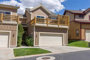 View of front facade with board and batten siding, a balcony, a shingled roof, and driveway