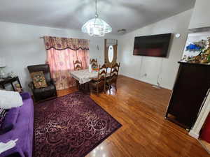 Dining area with dark wood finished floors, a chandelier, and vaulted ceiling