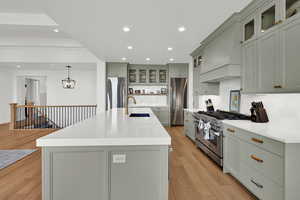 Kitchen with glass insert cabinets, recessed lighting, appliances with stainless steel finishes, hanging light fixtures, and backsplash