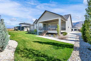 Back of property with covered porch, a lawn, a mountain view, an outdoor structure, and driveway