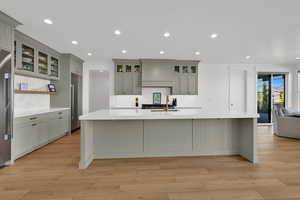 Kitchen featuring glass insert cabinets, recessed lighting, a large island, and gray cabinetry