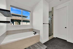Full bathroom featuring a stall shower, a bath, and dark tile patterned floors