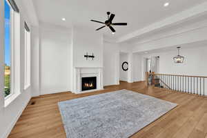Living room with a lit fireplace, light wood-style floors, recessed lighting, and a ceiling fan