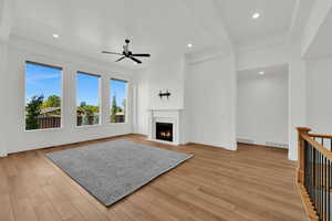 Unfurnished living room with a fireplace with flush hearth, beamed ceiling, light wood-style flooring, recessed lighting, and ceiling fan