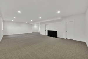 Finished basement with light carpet and recessed lighting