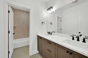 Bathroom with double vanity, light tile patterned flooring, and shower / bathtub combination