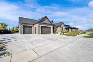 View of front of home featuring concrete driveway, an attached garage, stone siding, and a shingled roof