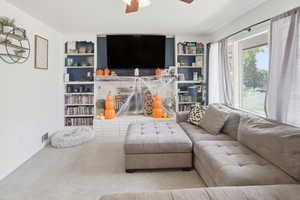 Carpeted living room with ceiling fan and baseboards