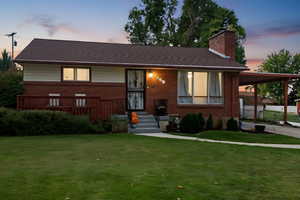 View of front of home featuring a lawn, a carport, and a chimney