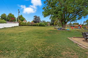 Fenced backyard featuring a playground and a patio