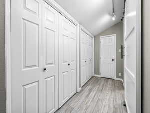 Corridor with lofted ceiling, a barn door, and light wood finished floors