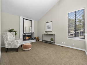 Sitting room featuring carpet, a fireplace, and vaulted ceiling