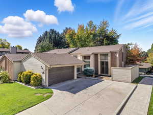 Mid-century inspired home featuring roof with shingles, concrete driveway, a front lawn, and brick siding