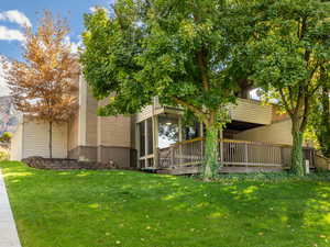 Back of property featuring a lawn and a deck