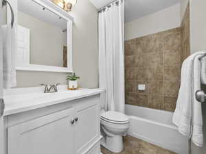 Full bathroom with vanity, shower / bath combo with shower curtain, and light tile patterned flooring
