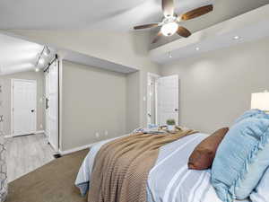 Bedroom featuring lofted ceiling, a barn door, carpet, track lighting, and recessed lighting