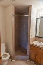 Full bath with vanity, light tile patterned flooring, a stall shower, and a textured ceiling