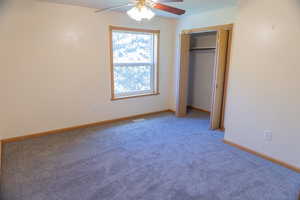 Unfurnished bedroom with ceiling fan, light colored carpet, and a closet