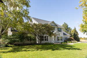 View of property hidden behind natural elements with a front lawn and roof with shingles