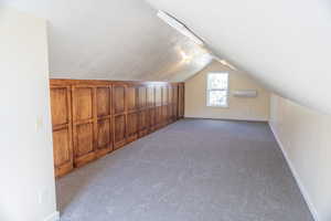 Bonus room featuring light carpet, lofted ceiling, and a wall unit AC