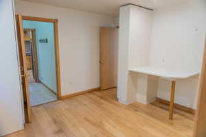 Unfurnished room featuring light wood-type flooring and built in desk
