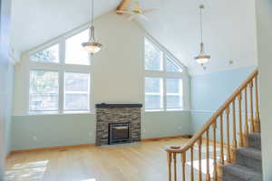 Unfurnished living room with stairway, beamed ceiling, wood finished floors, high vaulted ceiling, and a fireplace