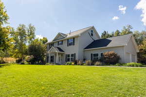 Colonial inspired home with a front yard, a garage, and roof with shingles