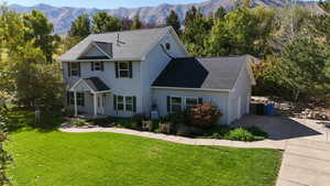 View of front of house with a front yard, a mountain view, and roof with shingles