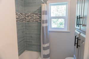 Full bath with shower / bath combination with curtain and plenty of natural light