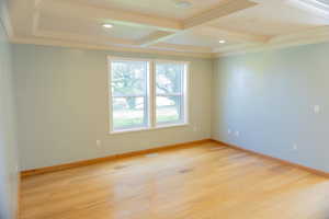 Unfurnished room featuring coffered ceiling, beamed ceiling, crown molding, light wood-style flooring, and recessed lighting