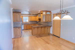 Kitchen featuring tasteful backsplash, decorative light fixtures, a kitchen bar, a peninsula, and dark stone countertops