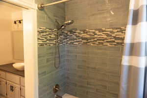Bathroom with shower / bath combination with curtain and vanity