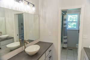 Bathroom with two vanities, light tile patterned flooring, and shower / tub combo