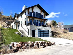 View of front of property with stone siding, driveway, a garage, a front yard, and a chimney