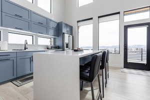 Kitchen featuring light stone countertops, a breakfast bar, light wood-style floors, high quality fridge, and decorative backsplash
