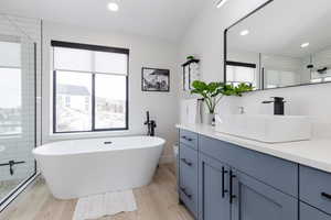Full bath featuring vanity, healthy amount of natural light, light wood finished floors, a shower stall, and recessed lighting