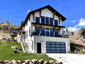 View of front facade featuring stone siding, driveway, a garage, a front yard, and a chimney
