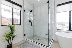 Full bathroom featuring a stall shower, a freestanding tub, and light wood-style flooring