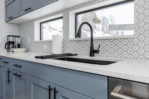 Kitchen featuring light stone countertops, decorative backsplash, blue cabinets, and gray cabinets